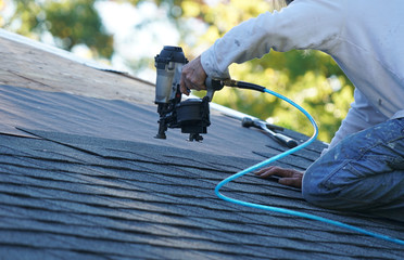 handyman using nail gun to install shingle to repair roof © nd700