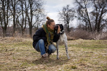 Young brunette girl with her dog walking in autumn park.