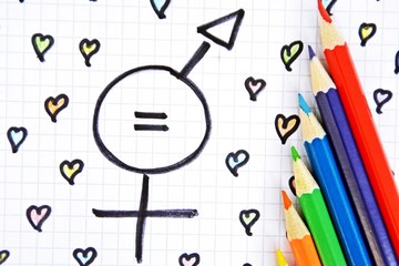 A sign for the equality of man and woman consisting of the respective gender signs and a match with painted hearts and colored pencils on a drawn sheet -equality man and woman symbolically represented