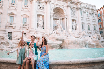 Happy family trowing coins at Trevi Fountain, Rome, for good luck. Little girls and parents making...