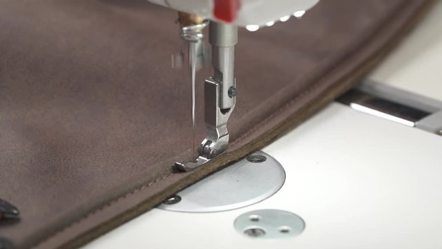 Leatherworker finishes sewing leather parts. Close-up of a tailor working with sewing machine. Leather stitching on sewing machine in action
