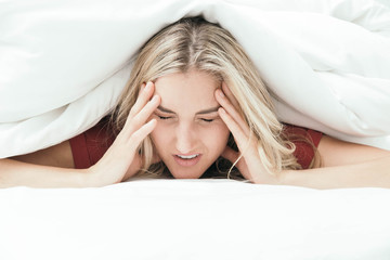 Fototapeta premium Grumpy blonde girl under white covers