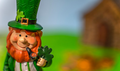 A happy leprechan in the forest in front of his gold.