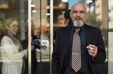 Mature senior man smoking in office door