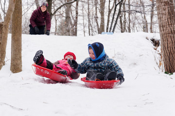 Brother and sisters (5 and 3 yrs old) sledging together in Quebec in winter