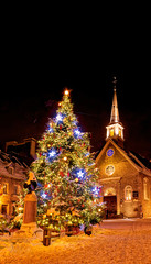 Christmas decorations and fresh snow in Quebec City's Petit Champlain area at night - in Place Royale with the church Eglise Notre Dame des Victoires
