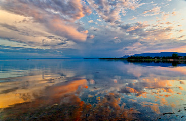 A dramatic sunset reflected in mirror calm waters of Maria, Baie des Chaleurs , Gaspesie in Quebec,...