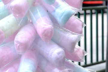 Close up a multicolored of cotton candy in a plastic packaging and a merchant selling on a street in the outdoor festival 
