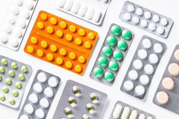 Pills in a blister and vitamins on white background flatlay.