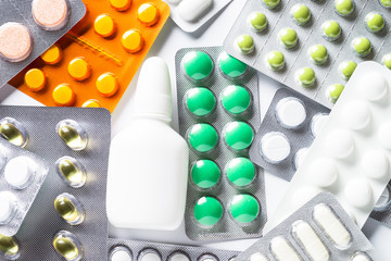 Pills in a blister and vitamins on white background flatlay.