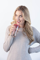 Blonde girl drinking water with a red and white straw from a glass with a red lid