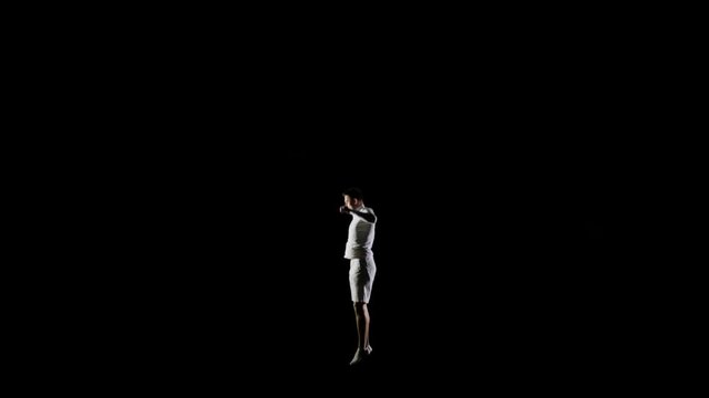 Athletic man in white clothes performs tricks jumping on a trampoline on a black monophonic background