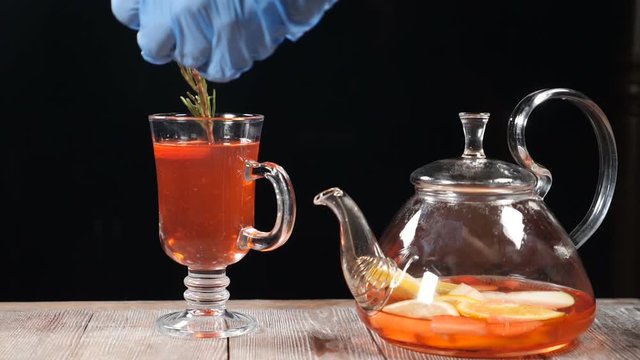 Final touch concept. Bartender puts rosemary leaves in glass with fruit tea. Slow motion. hd
