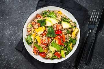 Quinoa salad with fresh vegetables on black.