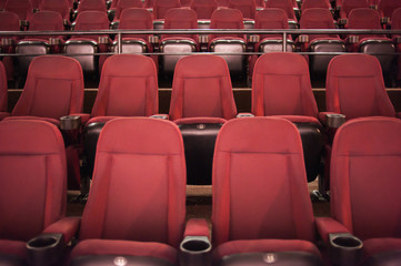 Empty cinema. Rows of comfortable red chairs towards to big screen in illuminate red room cinema. Mock Up.