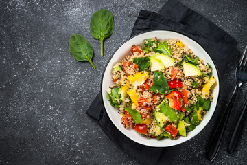 Quinoa salad with fresh vegetables on black.
