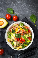 Quinoa salad with fresh vegetables on black.