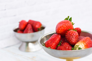 Bright ripe strawberry in a metal cups on a light background.