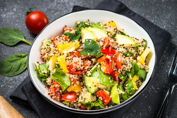 Quinoa salad with fresh vegetables on black.