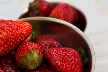 Ripe red strawberry closeup lies in a cup.