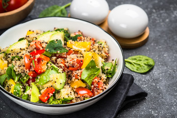 Quinoa salad with fresh vegetables on black.