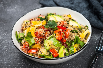 Quinoa salad with fresh vegetables on black.