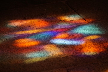 abstract colorful background of sunlight shining through stained glass window in a church on the stone floor