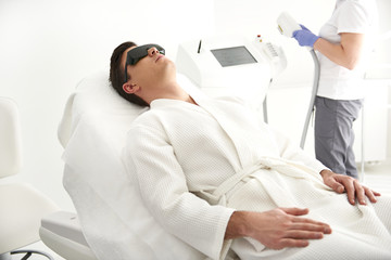 Young man lying on couch in laser epilation center
