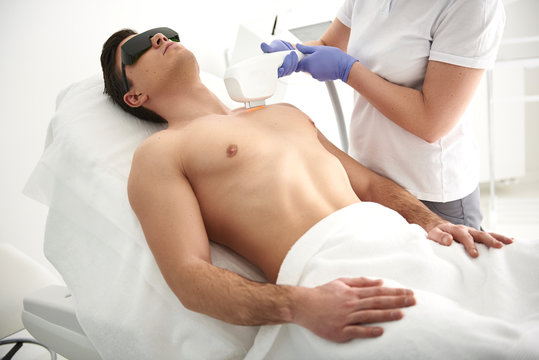 Female making laser epilation of chest to man
