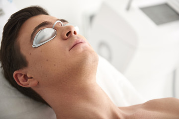 Man lying in cosmetic center with protection glass