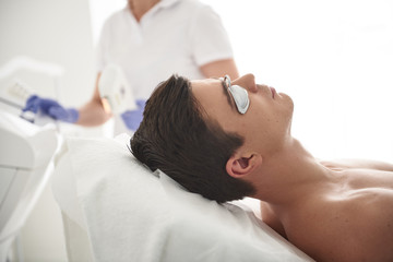 Obraz na płótnie Canvas Laser epilation procedure to young man in salon