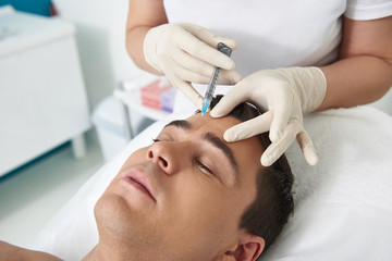 Young man lying on couch on botox procedure