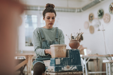 Beautiful young woman working on pottery wheel