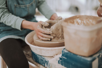 Young woman shaping clay on pottery wheel