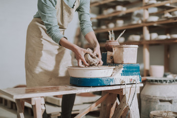 Young woman in apron making pottery in workshop