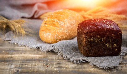 Fresh fragrant bread on a wooden table at sunset. Homemade hot pastry with.