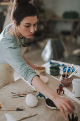 Beautiful young lady in apron working in pottery workshop