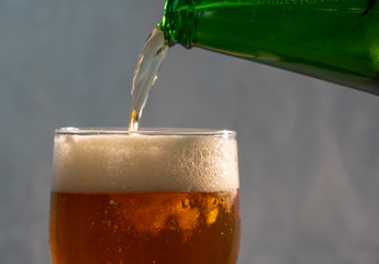 pouring beer into a glass from a green bottle