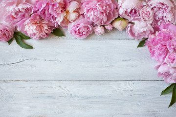 Pink peonies and roses on a wooden background