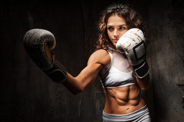 Sport young woman wearing boxing gloves posing in combat stance looking at camera. Fit young female...