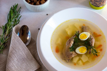 Delicious fragrant soup based on quail broth in a white dining plate. Slices of meat, quail egg, dill, bulgur, pepper and crackers - a useful and simple dish. Turkish cuisine.