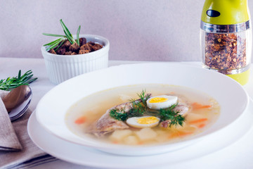 Delicious fragrant soup based on quail broth in a white dining plate. Slices of meat, quail egg, dill, bulgur, pepper and crackers - a useful and simple dish. Turkish cuisine.