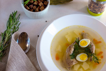 Delicious fragrant soup based on quail broth in a white dining plate. Slices of meat, quail egg, dill, bulgur, pepper and crackers - a useful and simple dish. Turkish cuisine.
