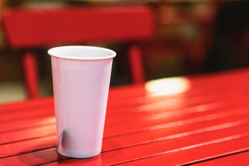 White paper cup with tea pocket on the red table