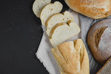 Bakery - gold rustic crusty loaves of bread on black chalkboard background. Flat lay, top view, copy space for your text