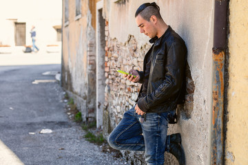 Half length portrait of male with  style using cell telephone while standing in urban setting