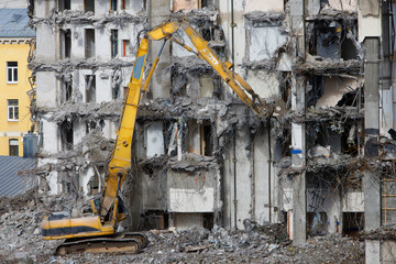 Fototapeta premium Budowa dawnego hotelu rozbiórka pod nową konstrukcję przy użyciu specjalnej hydraulicznej koparki-niszczarki. Zakończenie wysoce zmechanizowanej rozbiórki konstrukcji budowlanych. Koncepcja placu budowy