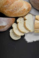 Bakery - gold rustic crusty loaves of bread on black chalkboard background. Flat lay, top view, copy space for your text