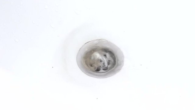 Water is drawn into the bath with hair in the drain hole of the bath, the water gurgles and rotates. Female hand pulls a bunch of hair from the drain hole