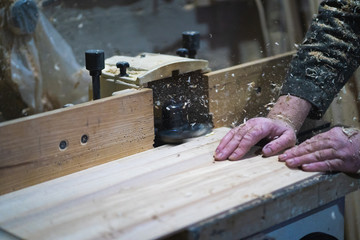 A man is working with wood on milling machine